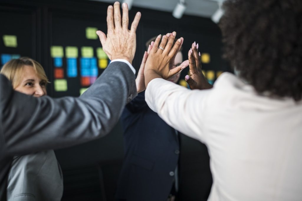 An image of happy coworkers giving a high five for implementing an inventory management software with a barcode system