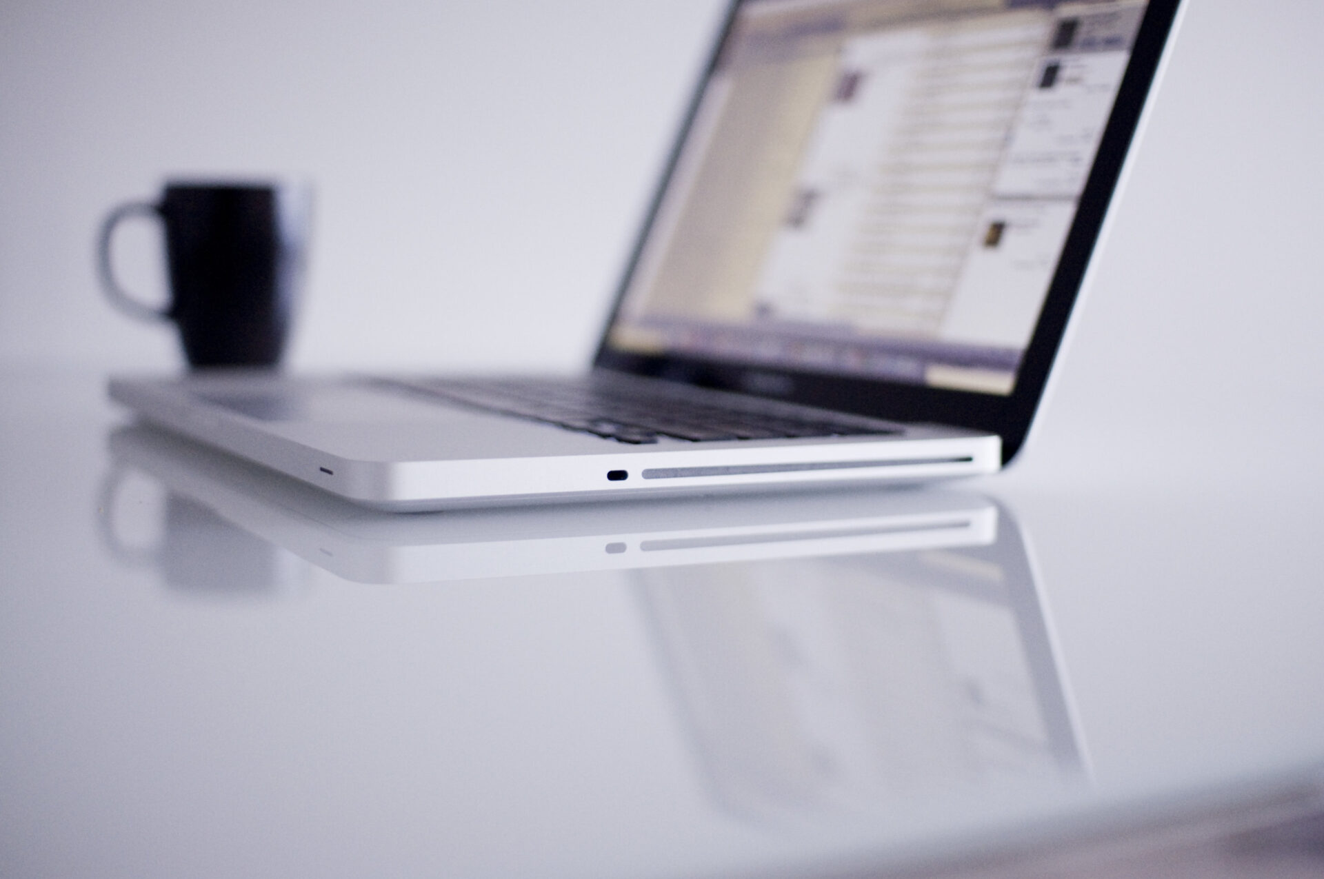 soft focus image of mac computer with black coffee mug