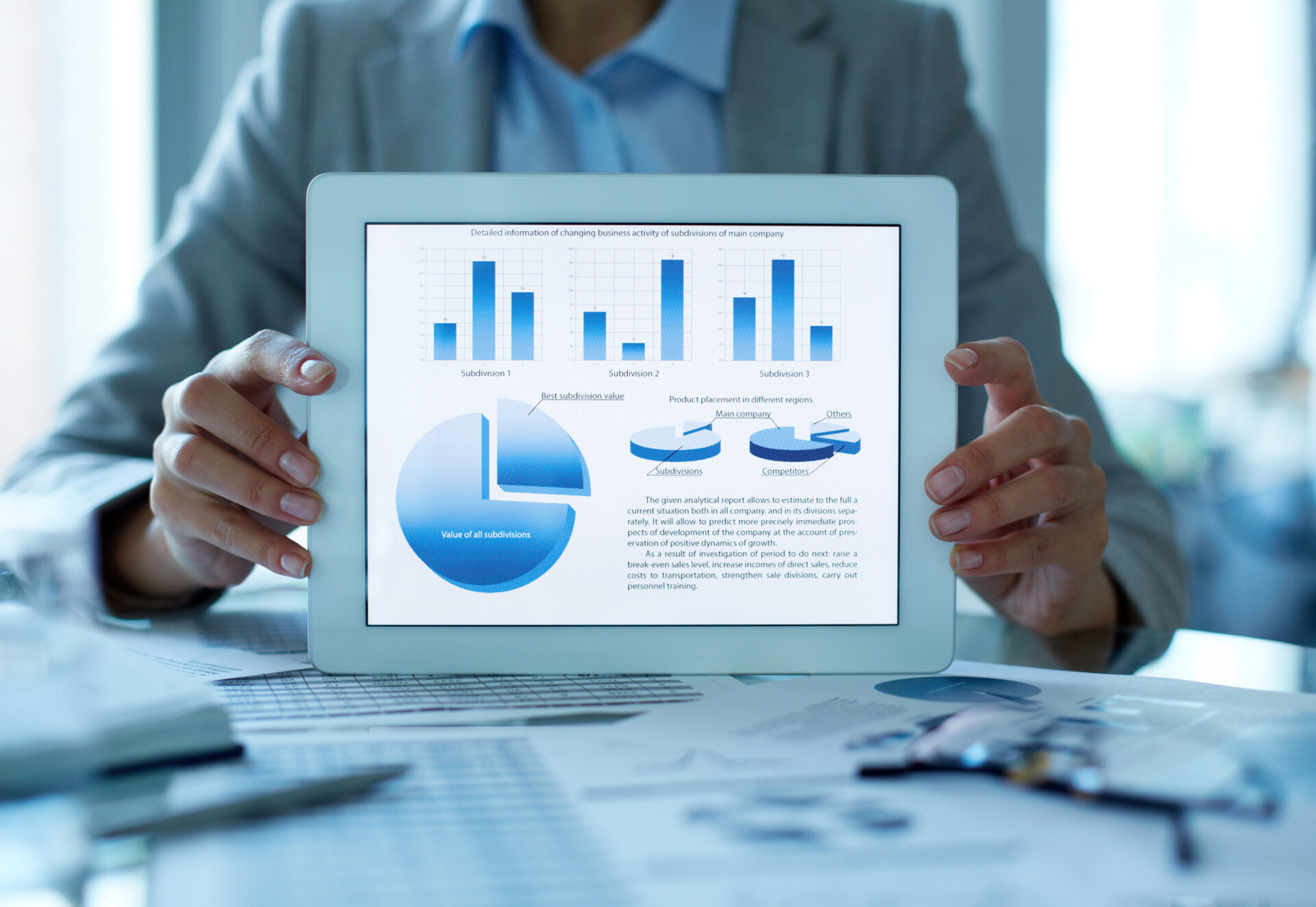 business woman holding up a tablet that displays charts and graphs