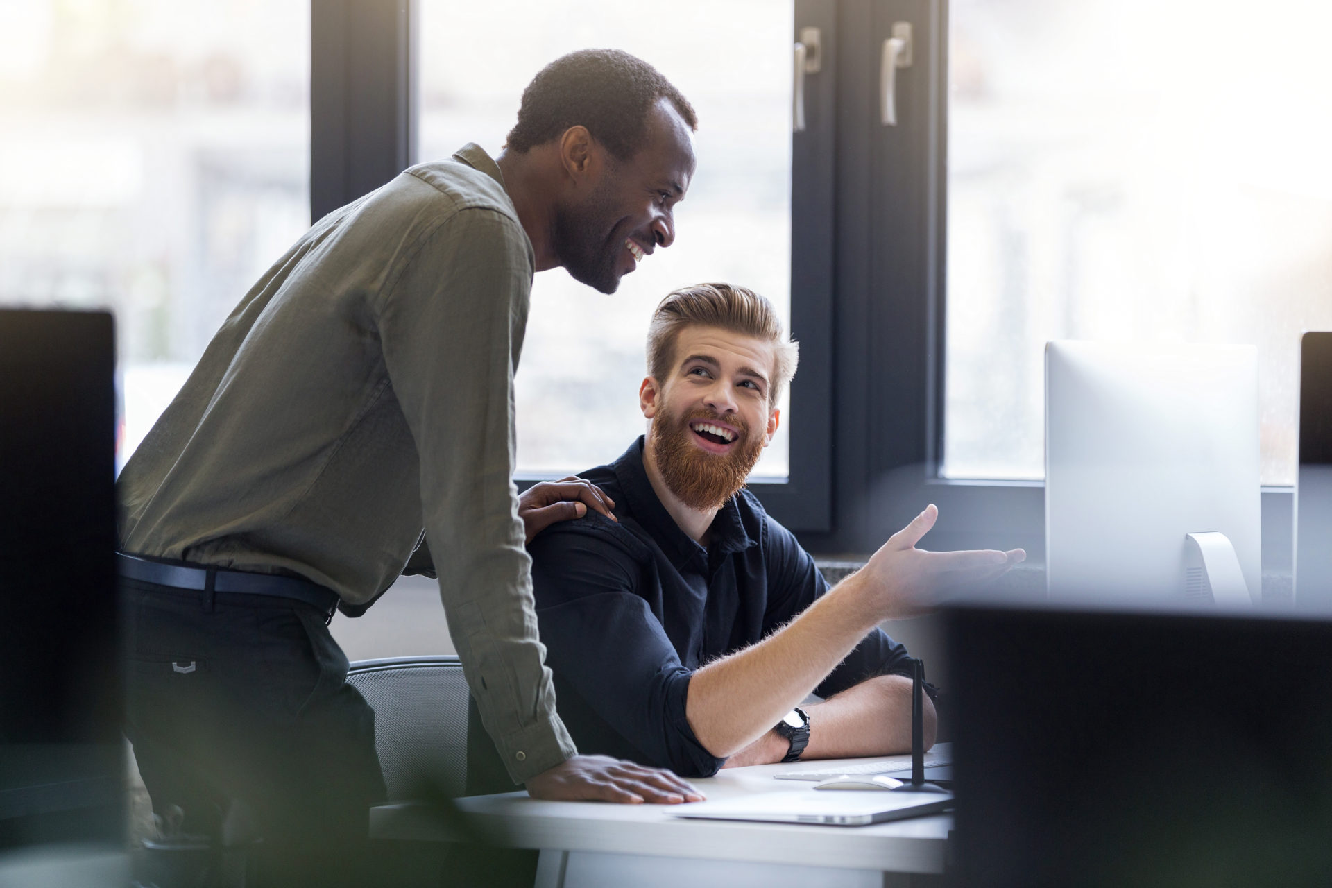 Two happy smiling men working together on a new business project at a workplace