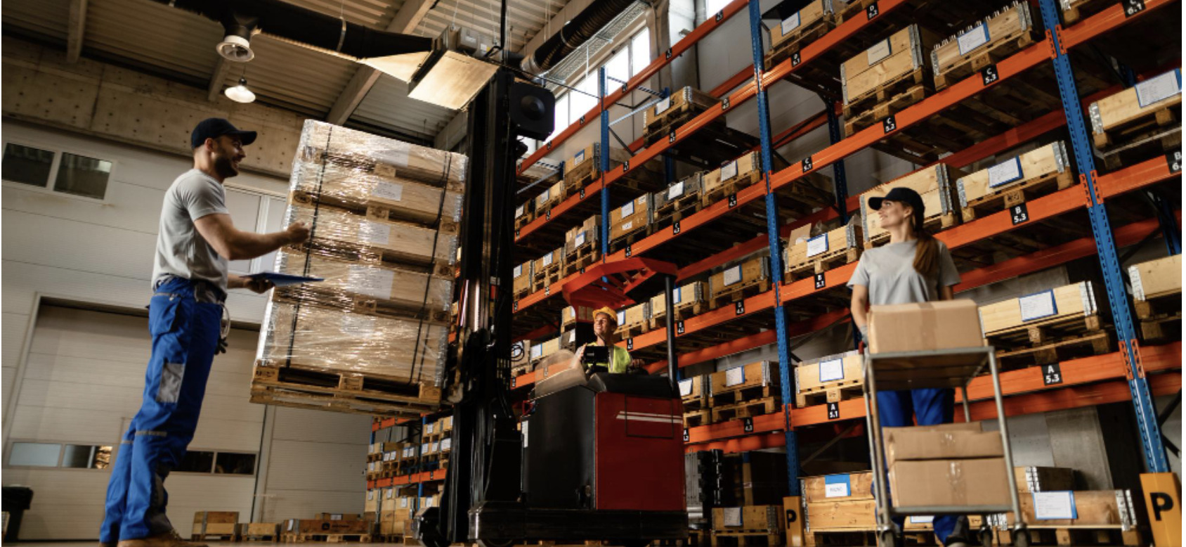 low angle view of happy warehouse workers communicating while working with shipment in industrial storage compartment