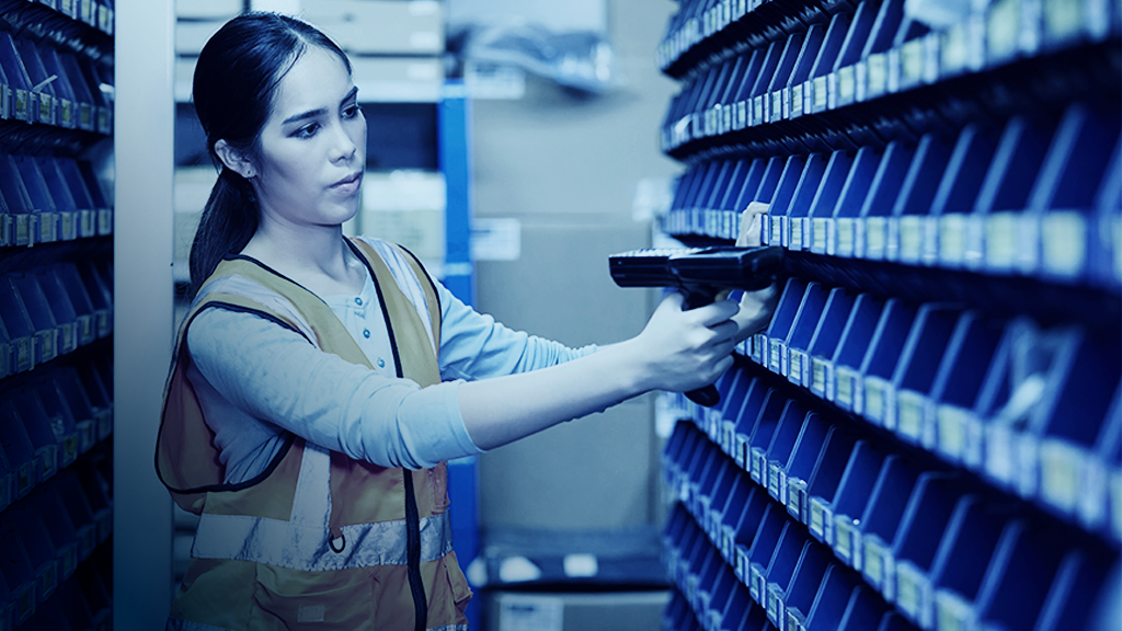 warehouse worker using laser barcode scanner to track inventory in bins