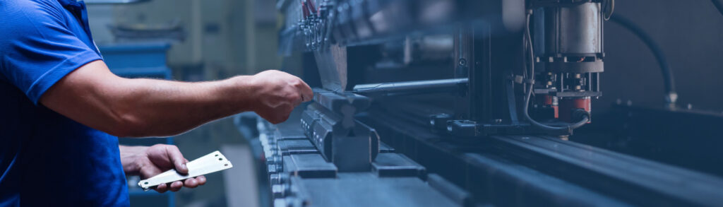 a worker in a manufacturing facility using raw materials for production with heavy equipment.