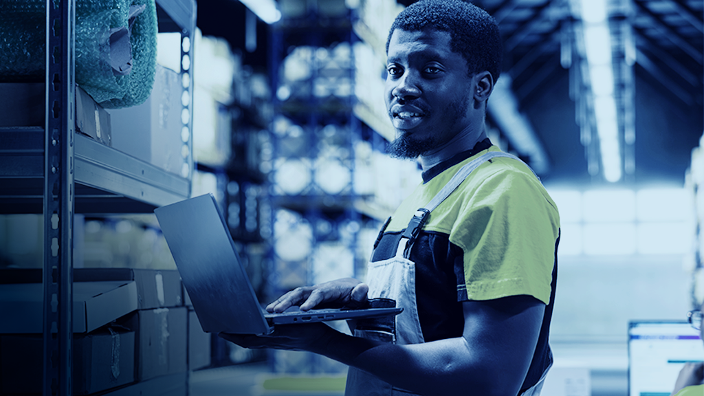 Warehouse worker overseeing inventory for ecommerce order fulfillment. Shelving merchandise and updating tracking labels on laptop for order fulfillment.