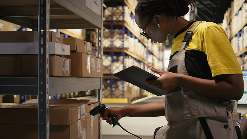 inventory-management-featured_image eCommerce worker scanning shipping labels numbers, registering awb and shipment details for the inventory records